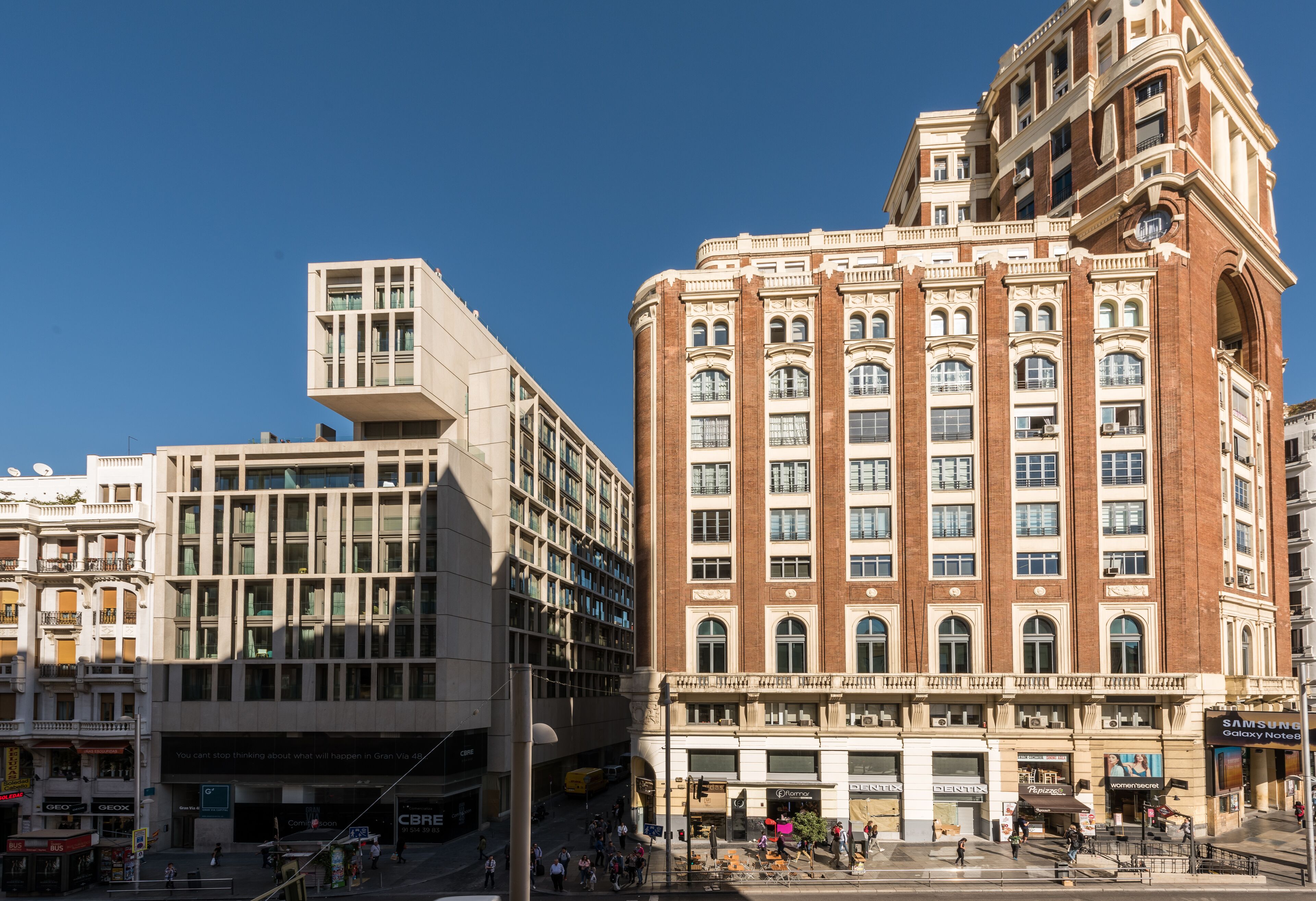 A multi-story building with a mix of modern and classical architectural styles, featuring large windows and a prominent corner tower.
