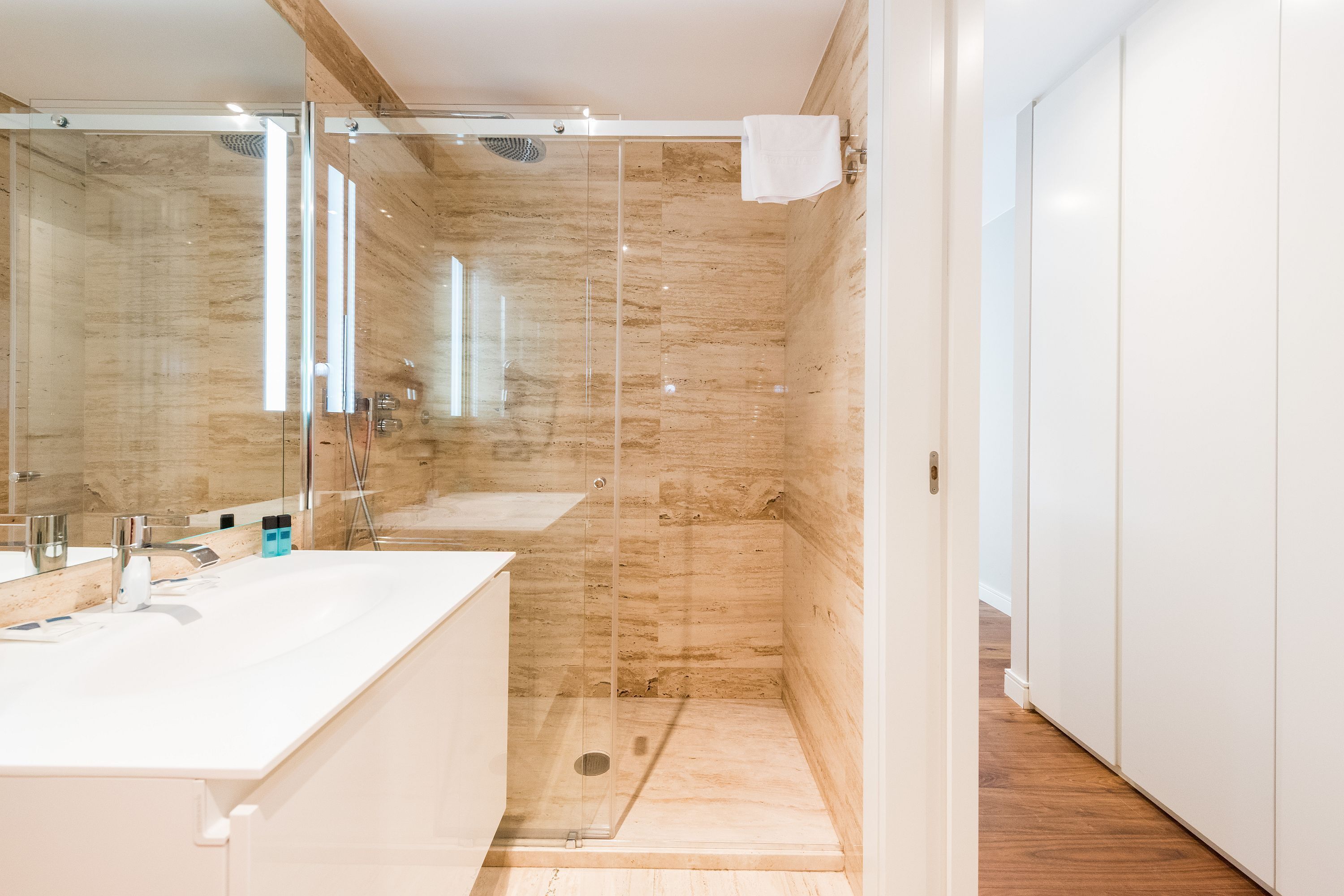 A modern bathroom with a glass-enclosed shower, a white sink, and a large mirror.