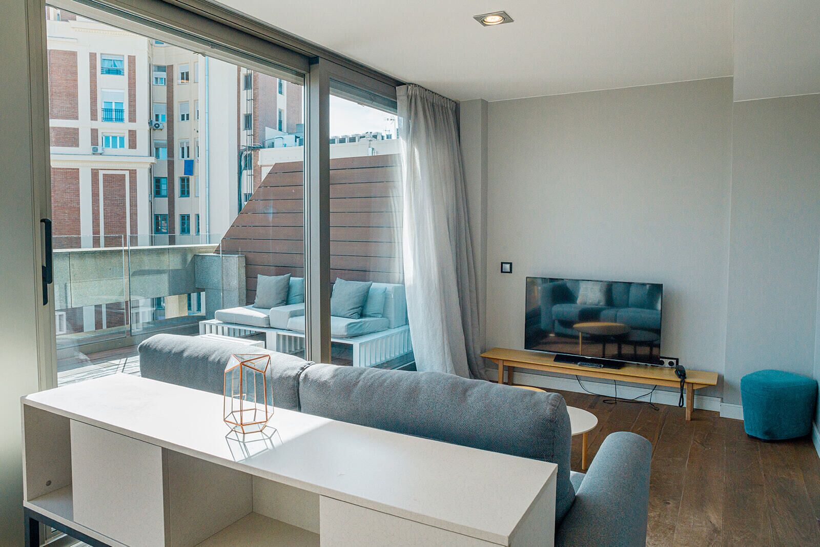 A modern living room with a sofa, a TV, and a dining area.