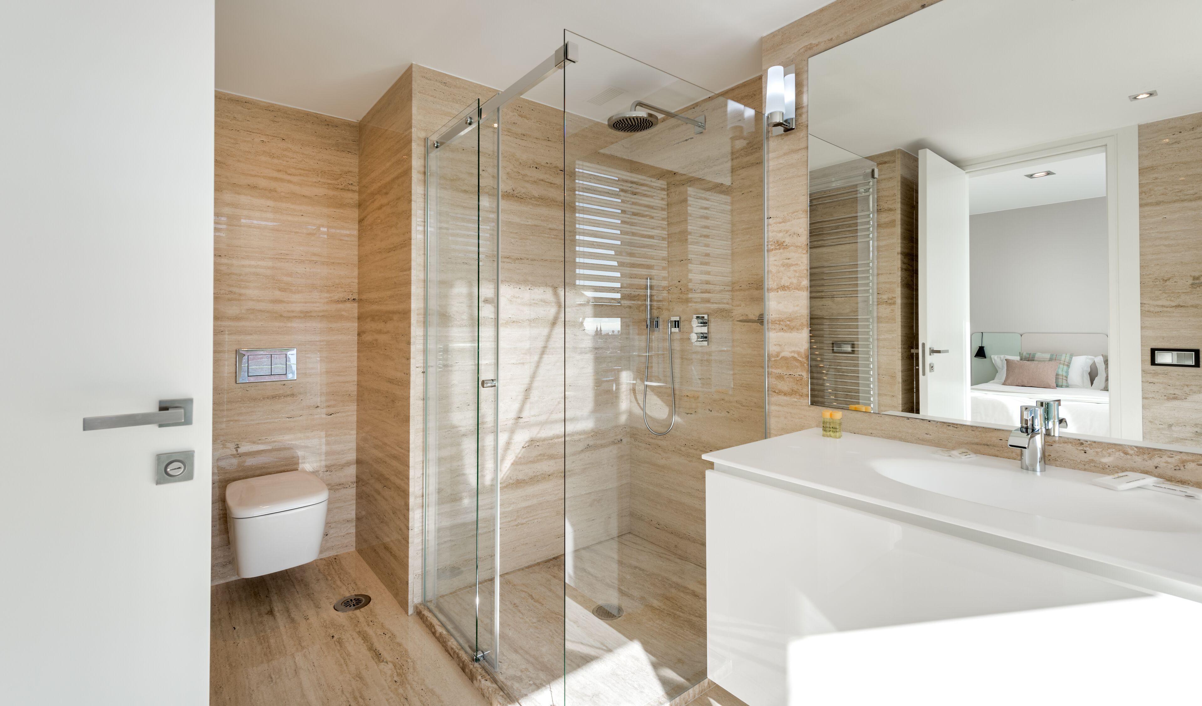 A modern bathroom with a glass-enclosed shower, a white sink, and a large mirror.