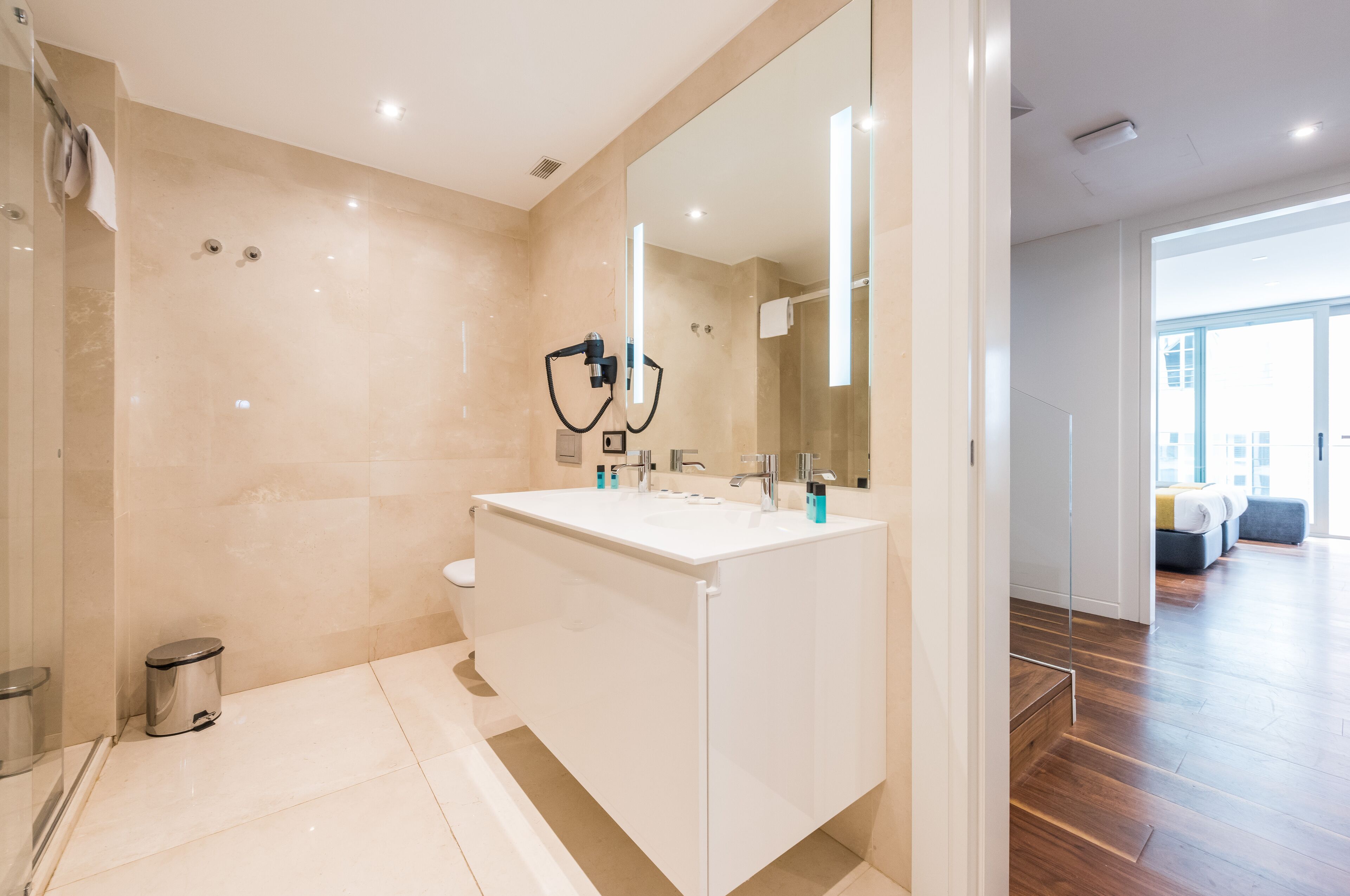 Une salle de bain moderne avec un grand miroir, un lavabo blanc et un espace douche.