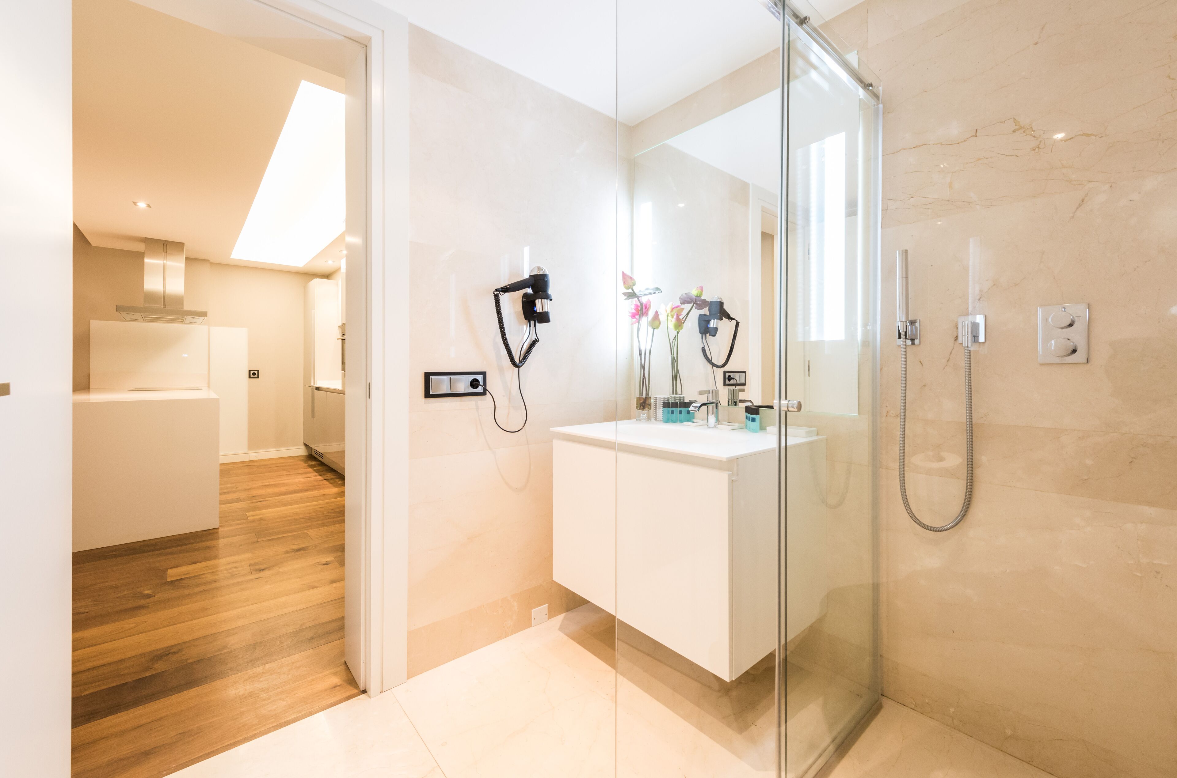 A modern bathroom with a glass shower enclosure, a white vanity, and a skylight.