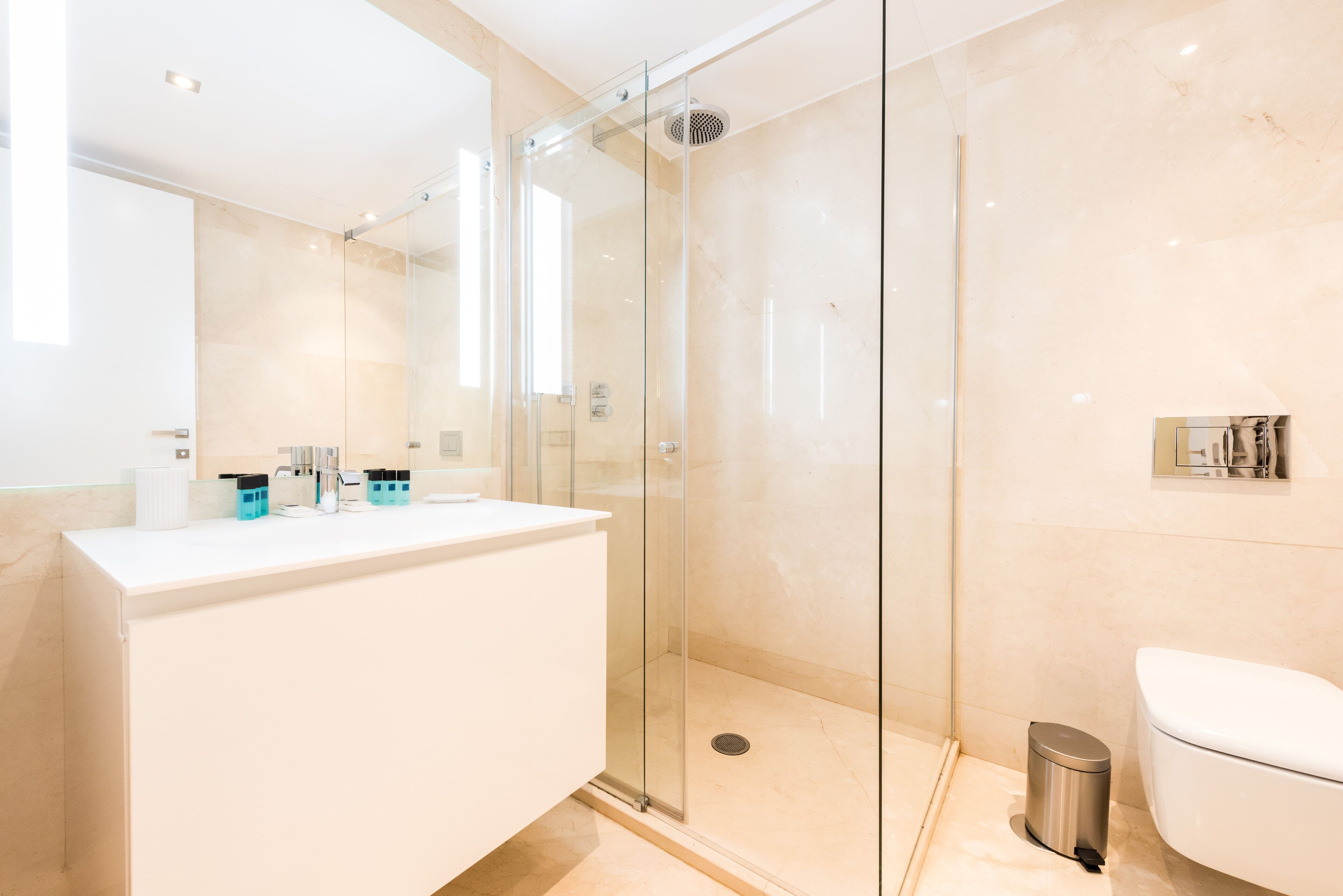 A modern bathroom with a glass-enclosed shower, a white sink, and a toilet.