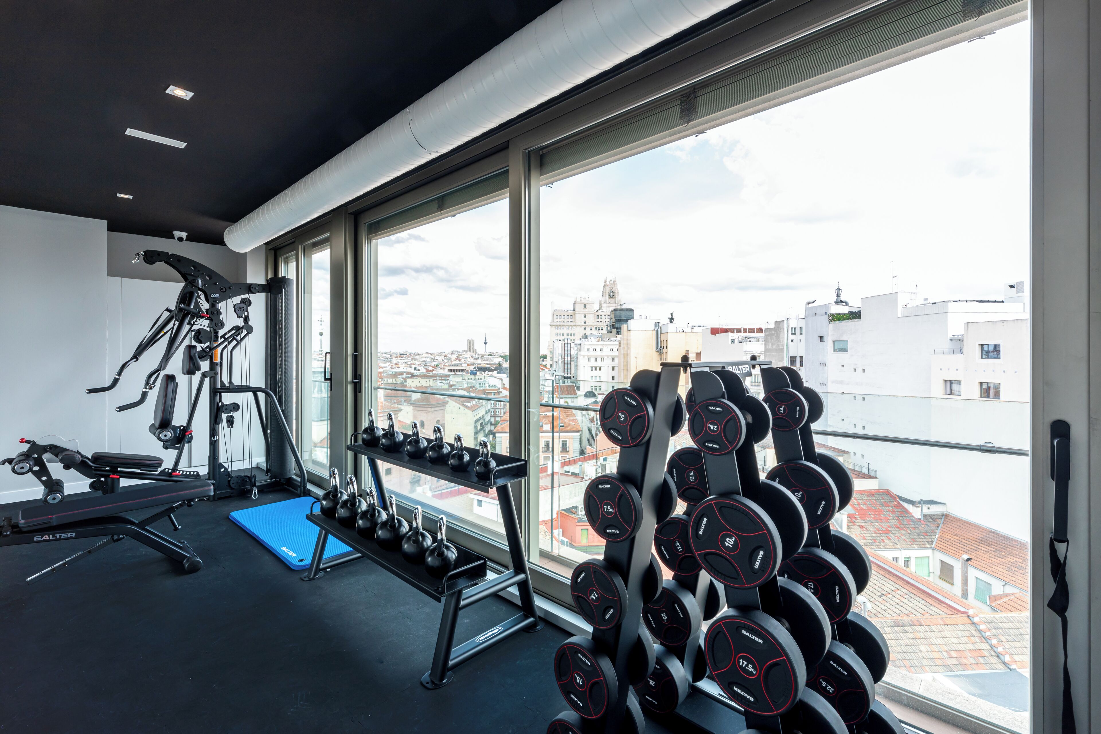 A gym with exercise equipment and a rack of dumbbells.