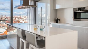 A modern kitchen with a large window, white cabinetry, and a stainless steel oven. - Gran View Apartments (Madrid)