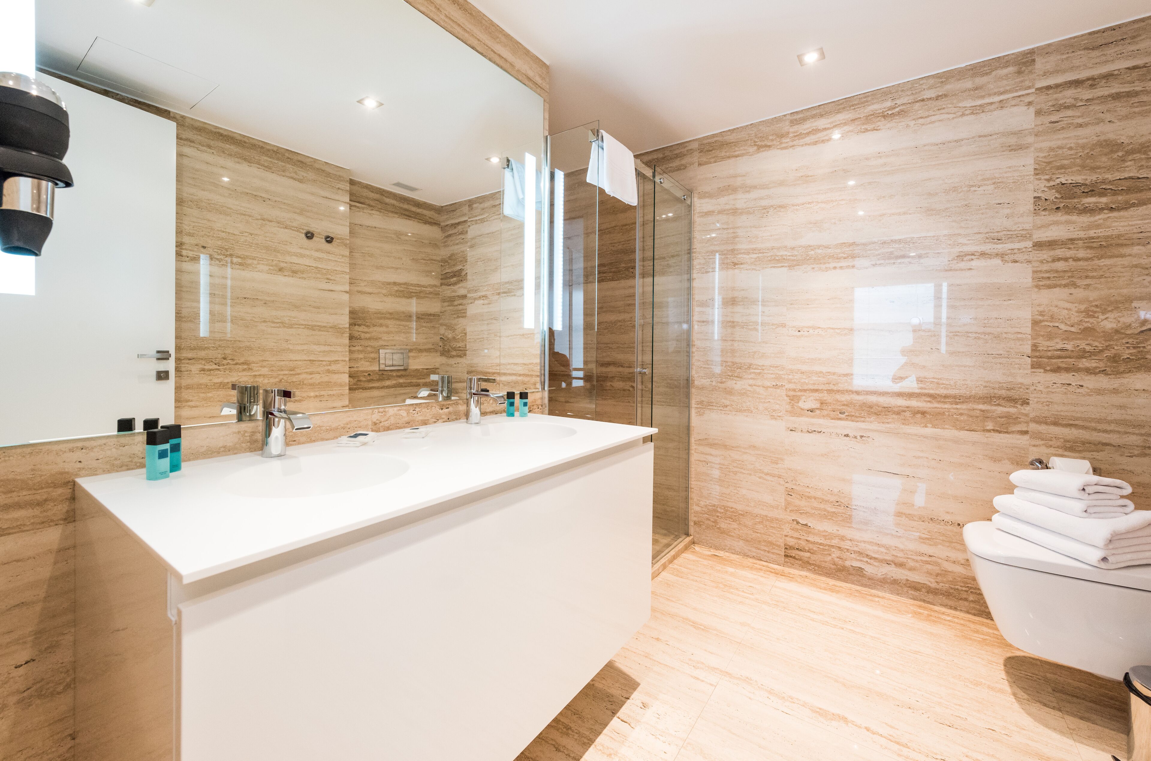 A modern bathroom with a large mirror, a white sink, and a glass shower enclosure.