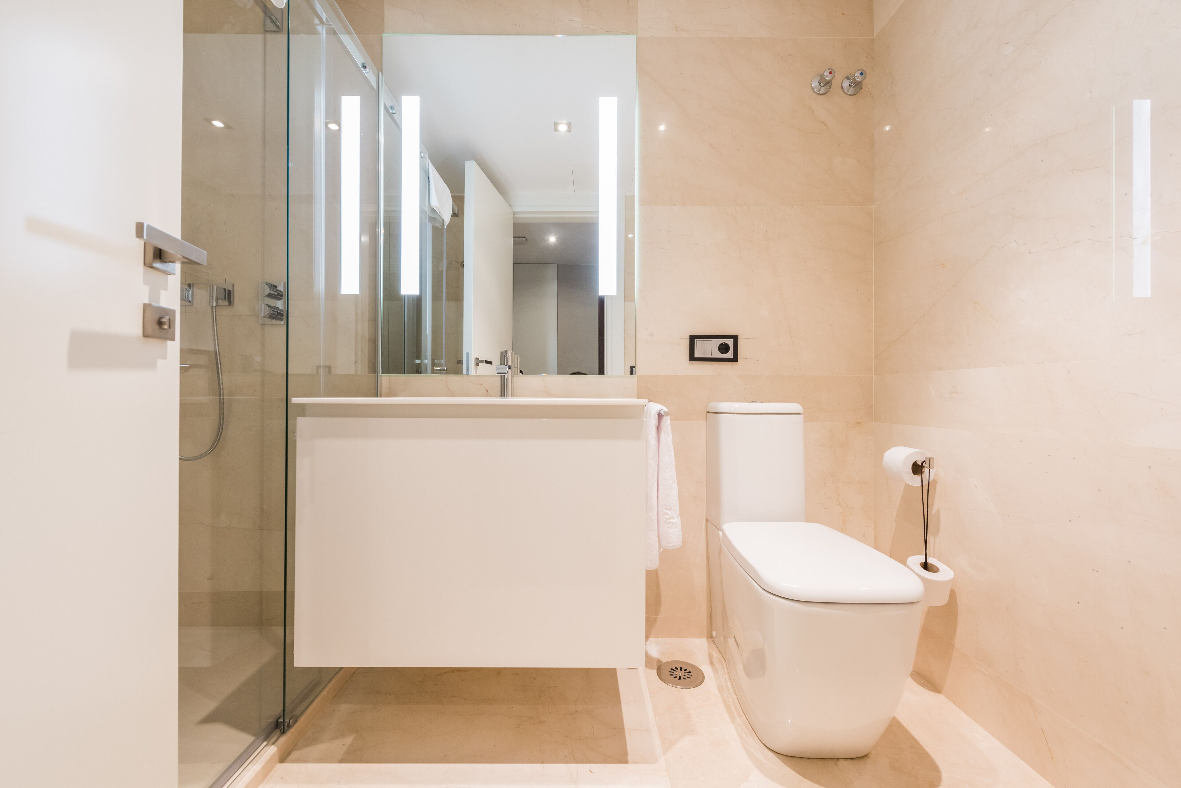 A modern bathroom with a glass shower enclosure, a white bathtub, and a toilet.