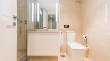 Ein modernes Badezimmer mit Duschkabine aus Glas, einer weißen Badewanne und einem WC.