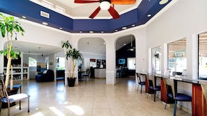 A spacious lobby with a high ceiling, a central plant, a seating area, and a reception desk.
