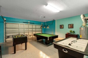 Une pièce équipée d’une table de billard, d’un baby-foot et d’une porte de garage.