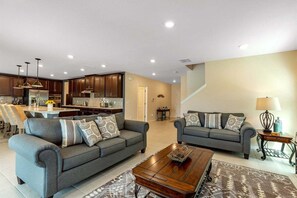 A modern living room with two sofas, a coffee table, and a kitchen in the background.