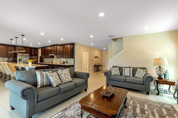A modern living room with two sofas, a coffee table, and a kitchen in the background.