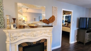 Un salon avec une cheminée, des miroirs décoratifs et un téléviseur.