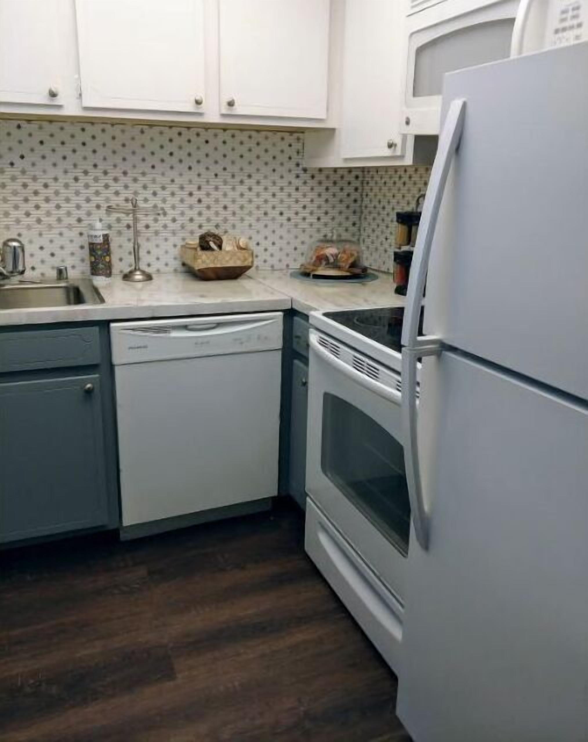 Une cuisine avec des meubles blancs, un lave-vaisselle, un four et un four à micro-ondes.