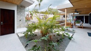 Un patio extérieur moderne avec un mur en pierre, un plafond en bois et un espace détente comprenant des chaises et une table.