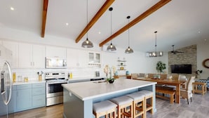 Une cuisine moderne avec des meubles blancs, des appareils en acier inoxydable et un îlot central doté de tabourets de bar.