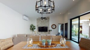 Un coin repas avec une table en bois, deux plantes en pot et un lustre.