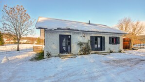 A single-story house with a snow-covered roof and a front door.