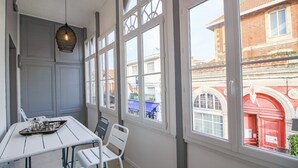 En matplats med ett bord dukat för två personer, stora fönster med dekorativa galler och en hängande lampa.