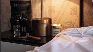 A neatly made bed with a white comforter, a bedside table with a lamp, a radio, and a candle. - Enjoy your stay right  in the heart of Morelia (Morelia)