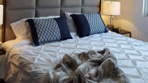 A hotel room with a large bed, two bedside lamps, a patterned headboard, and a window on the right. - Enjoy your stay right  in the heart of Morelia (Morelia)
