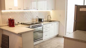 A modern kitchen with white cabinets, a gas stove, a built-in oven, and a stainless steel refrigerator. - Enjoy your stay right  in the heart of Morelia (Morelia)