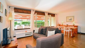 Ein Wohnzimmer mit einer Couch, einem Fernseher und einem Essbereich mit Stühlen und einem Tisch.
