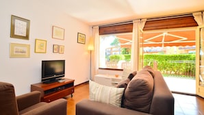 Ein Wohnzimmer mit Fernseher, Sofa und einem Balkon mit Tisch und Stühlen.