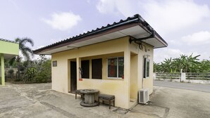 A small, single-story building with a tiled roof and a concrete floor. There is a table and a bench outside. - OYO 75392 Phachuen Resort (Sattahip)