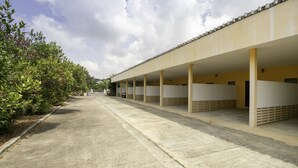 A row of single-story buildings with covered parking spaces and a concrete pathway. - OYO 75392 Phachuen Resort (Sattahip)