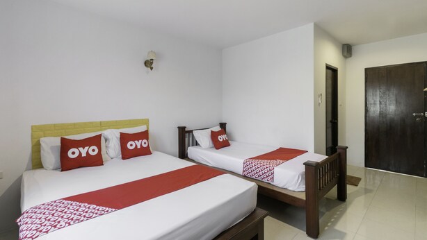 Two single beds with wooden frames and white bedding, each with a red pillow and a red blanket. - OYO 75392 Phachuen Resort (Sattahip)