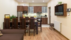 A compact kitchen with wooden cabinets, a microwave, a stove, and a built-in TV. - KrakowRentals - Vanilla 5 Apartment (Kraków)