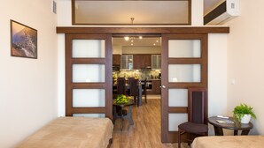 A hotel room with two beds, a small table with a plant, and a view into the kitchen area. - KrakowRentals - Vanilla 5 Apartment (Kraków)