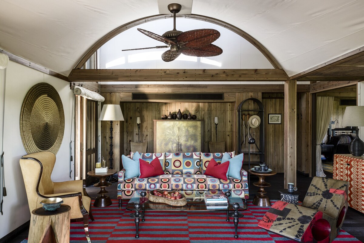 A cozy room with a wooden ceiling, a patterned sofa, a coffee table, and a ceiling fan.