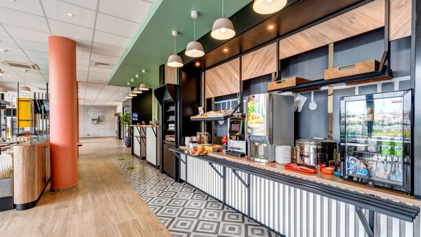 Eine moderne Cafeteria mit einer langen Theke, verschiedenen Speisen und einem Kühlschrank.