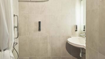 Een moderne badkamer met een douche, wastafel en spiegel.