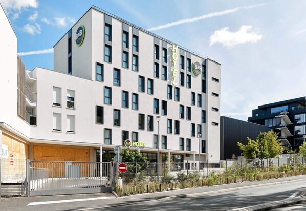 A modern hotel with a white facade, multiple windows, and a visible entrance with a gated driveway. - B&B HOTEL Champigny-sur-Marne (Champigny-sur-Marne)