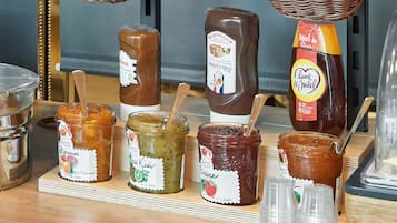 Verschiedene Gläser mit Marmelade und Soßen auf einer Holzbrett, mit deutlichen Etiketten und Holzlöffeln.