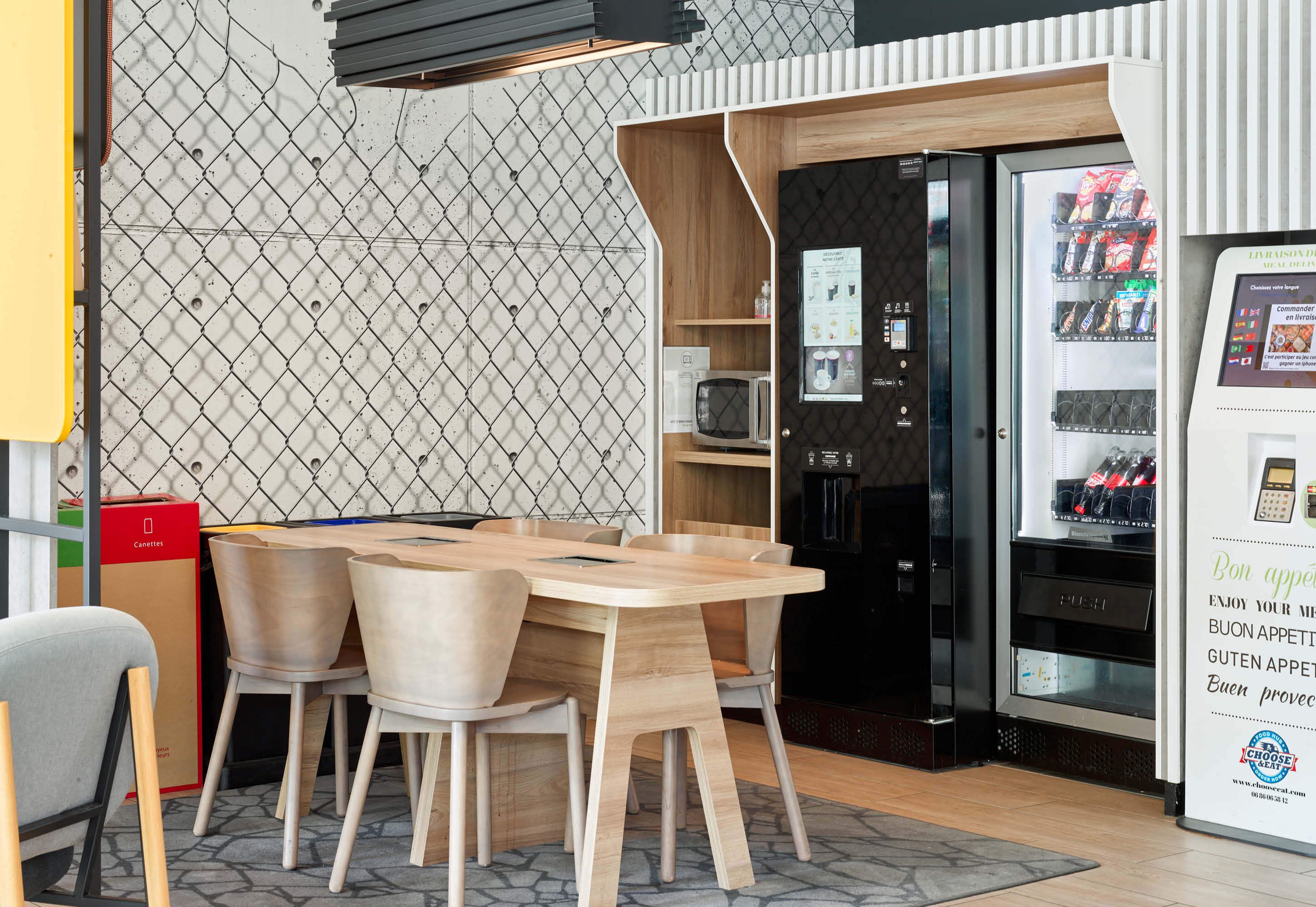A modern interior with a wooden dining table and chairs, a vending machine, and a microwave.