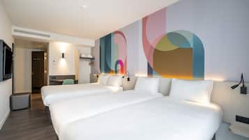 A hotel room with two beds, a desk, and a large abstract wall art piece.