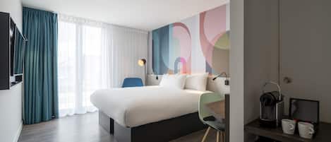 Une chambre d’hôtel moderne dotée d’un grand lit, d’un bureau avec une chaise, d’une télévision et d’une machine à café.