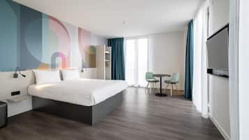 Une chambre d’hôtel moderne équipée d’un grand lit, d’un bureau, d’une chaise et d’un téléviseur.