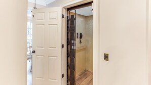 A hotel room with a wooden floor, a white door, and a view of the hallway. - Chic Townhome One Block From Forsyth w/ Large Garage by Lucky Savannah (Savannah)