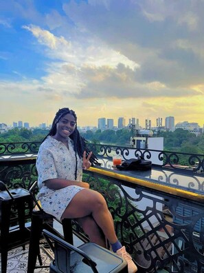 A person sitting on a balcony with a cityscape view. - Hanoi Media Hotel And Spa (Hanoi)