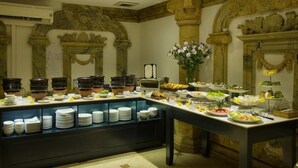 A buffet setup with various food items and a decorative wall with classical architecture. - Hanoi Media Hotel And Spa (Hanoi)