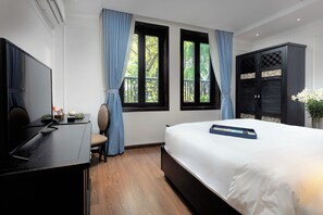 A hotel room with a bed, a desk, a chair, a TV, and two windows with curtains. - Hanoi Media Hotel And Spa (Hanoi)