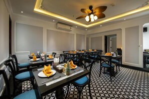 A conference room with multiple tables, chairs, and a ceiling fan.
