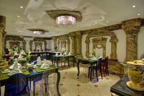 A dining area with tables set for service, ornate columns, and a chandelier. - Hanoi Media Hotel And Spa (Hanoi)