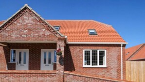 A brick house with a red-tiled roof, two white-framed windows, and a small dormer window. - Dawson Park 4 - UK12663 (Mablethorpe)