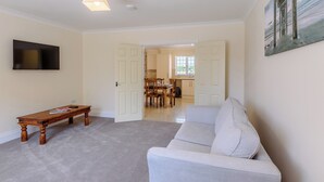 A living room with a flat-screen TV, a wooden coffee table, a light-colored sofa, and a painting on the wall. - Dawson Park 4 - UK12663 (Mablethorpe)